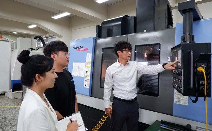 폴리텍대 창원캠퍼스 기계시스템과 학생들이 CNC 머시닝센터 장비 조작법에 대한 설명을 듣고 있다.