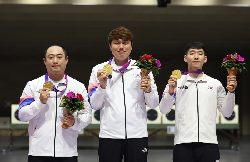 25일 중국 항저우 푸양 인후 스포츠센터에서 열린 제19회 항저우 아시안게임 남자 10m 러닝타깃 단체전에서 금메달을 획득한 하광철, 정유진, 곽용빈(왼쪽부터)이 시상대에서 메달을 들어보이고 있다. 연합뉴스