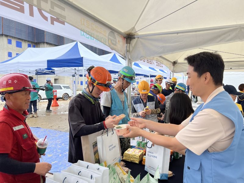 지난 26일 경기 광명시 재개발사업현장에서 포스코이앤씨 직원이 외국인근로자에게 추석선물을 주고 있다. 포스코이앤씨 제공