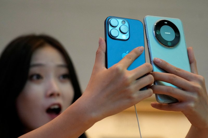 중국의 한 여성이 애플의 아이폰 15 프로와 화웨이 메이트 60 프로를 살펴보며 깜짝 놀라고 있다. 로이터연합뉴스