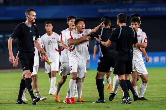 북한 남자축구 대표팀이 항저우 아시안게임 8강전에서 일본에 패한 뒤 주심에게 거칠게 항의하고 있다. AP연합뉴스