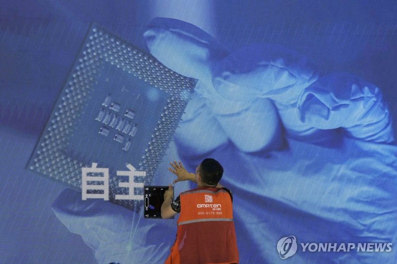 중국 반도체 A worker checks the display panel showing a computer chip and the Chinese words for "Independence" at the booth for Chinese supercomputer manufacturer Sugon during the World AI Conference in Shanghai, Wednesday, July 5, 2023. China's government appealed to Japan on Monday, July 24, not to dis