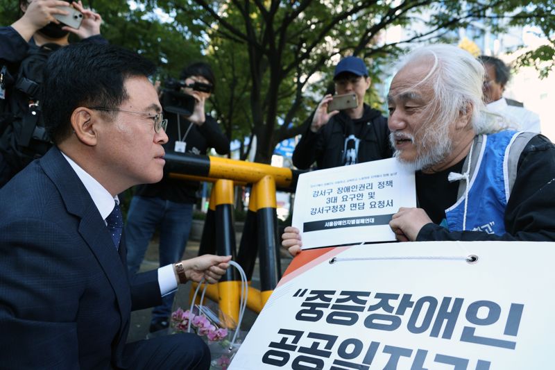 보궐선거에서 당선된 진교훈 신임 강서구청장이 12일 오전 서울 강서구청으로 첫 출근을 하던 도중 서울장애인차별철폐연대 회원으로부터 구청장 면담서를 전달받고 있다. 사진=서동일 기자