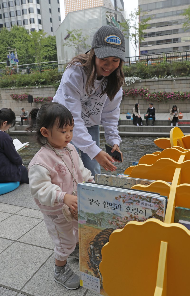 [서울=뉴시스] 김금보 기자 = 13일 서울 중구 청계천에 마련된 '책읽는 맑은냇가' 서울야외도서관을 찾은 어린이가 책을 고르고 있다. 서울도서관은 오는 15일까지 청계천 청계광장~모전교~광통교 구간에 책바구니를 비치하고 독서 구역으로 구성해 야외도서관으로 운영한다. 2023.10.13. kgb@newsis.com