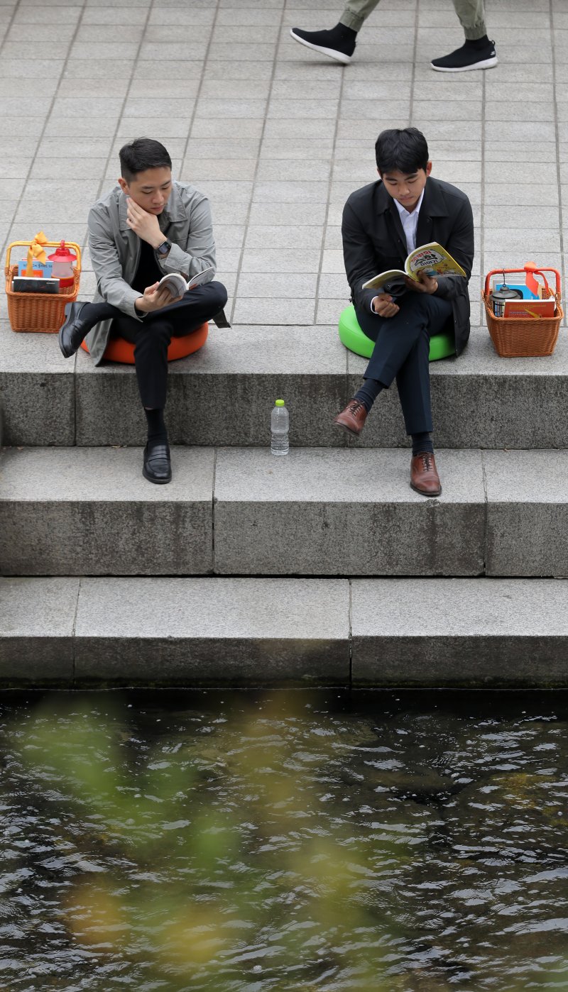 [서울=뉴시스] 김금보 기자 = 13일 서울 중구 청계천에 마련된 '책읽는 맑은냇가' 서울야외도서관을 찾은 시민들이 독서하며 휴식하고 있다. 서울도서관은 오는 15일까지 청계천 청계광장~모전교~광통교 구간에 책바구니를 비치하고 독서 구역으로 구성해 야외도서관으로 운영한다. 2023.10.13. kgb@newsis.com