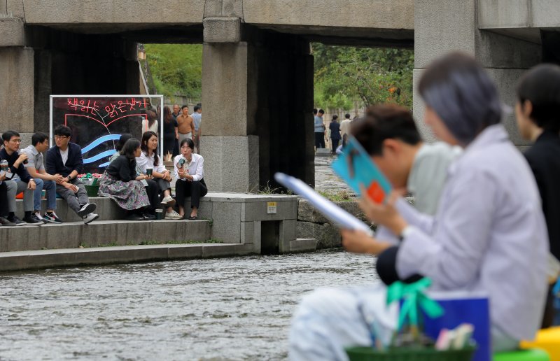 [서울=뉴시스] 김금보 기자 = 13일 서울 중구 청계천에 마련된 '책읽는 맑은냇가' 서울야외도서관을 찾은 시민들이 독서하며 휴식하고 있다. 서울도서관은 오는 15일까지 청계천 청계광장~모전교~광통교 구간에 책바구니를 비치하고 독서 구역으로 구성해 야외도서관으로 운영한다. 2023.10.13. kgb@newsis.com