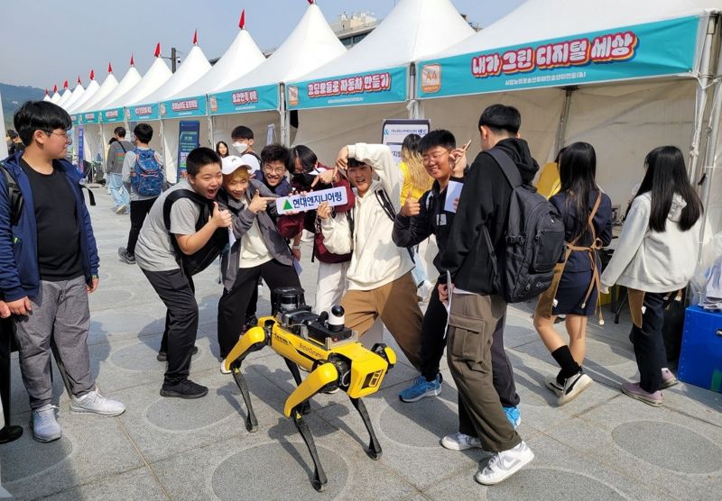 지난 18일 서울 광화문광장 놀이마당에서 열린 ‘2023 종로구 청소년진로직업박람회’에 참가한 학생들이 현대엔지니어링의 4족 보행 로봇 ‘스팟’과 함께 포즈를 취하고 있다. 현대엔지니어링 제공