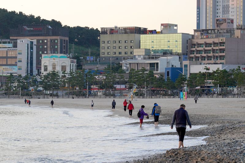 울산 동구 일산해수욕장에서 시민들이 퇴근 후 맨발걷기로 하루의 피로를 풀고 있다. 울산 동구는 맨발걷기가 최근 인기를 얻자 해변 옆에 800m 길이의 맨발걷기 산책로 코스를 따로 만들어 시민들이 안전하게 걷을 수 있도록 했다. 울산 동구 제공