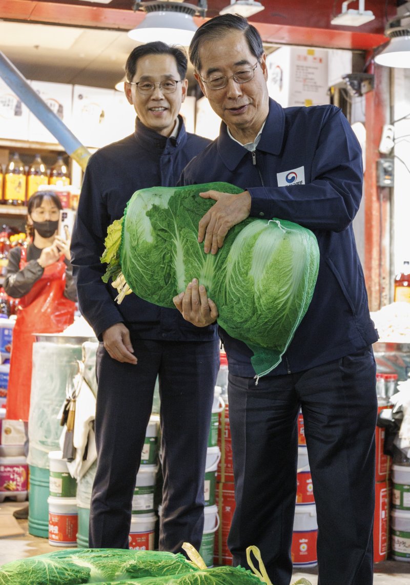 한덕수 국무총리(오른쪽)가 24일 오후 농수산물 물가 점검을 위해 서울 마포구 마포농수산물시장을 찾아 직접 배추를 골라 구입하고 있다. 연합뉴스