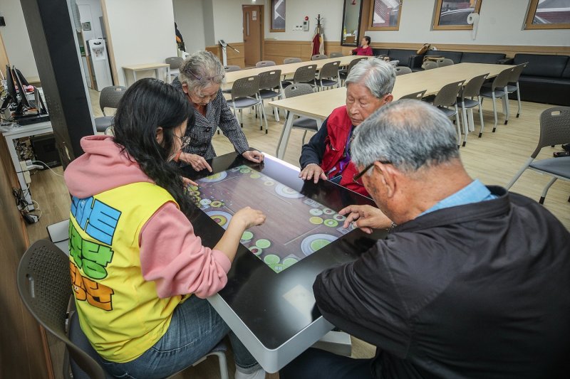 서울 양천구 신월동 신원경로당에 적용된 스마트경로당에서 어르신들이 스마트경로당 동행단과 함께 스마트테이블을 이용한 게임을 즐기고 있다. 서울시 제공