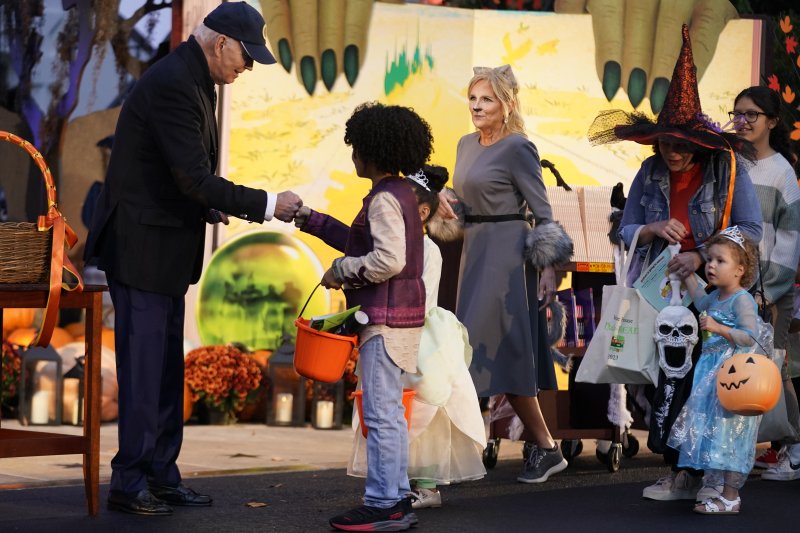 미국의 조 바이든 대통령(왼쪽)이 30일(현지시간) 미 워싱턴DC 백악관에서 고양이 분장을 한 질 바이든 영부인과 함께 아이들에게 사탕을 나눠주고 있다.AP뉴시스