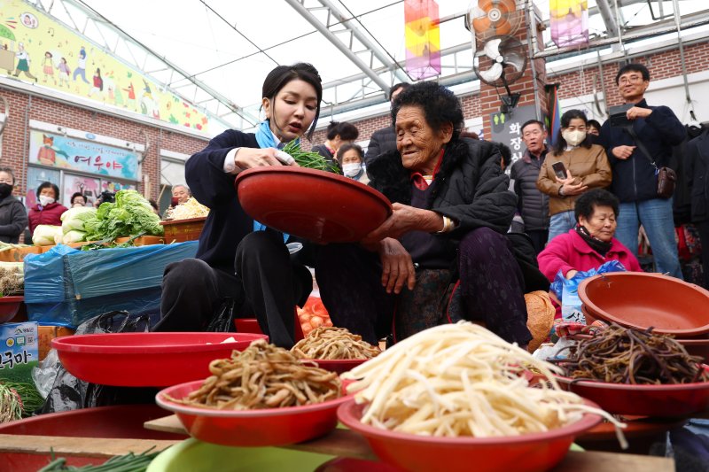 김건희 여사가 7일 전남 순천시 아랫장의 나물야채 가게에서 야채를 구매하고 있다. [대통령실통신사진기자단] 연합뉴스