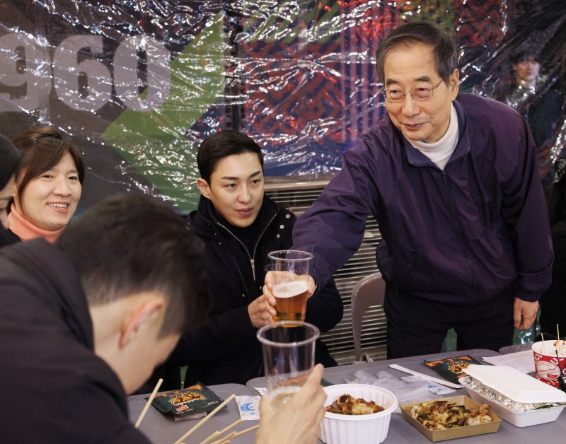 한덕수 국무총리가 11일 밤 서울 동대문구 경동시장 신관 옥상에 새롭게 문을 연 '경동시장1960' 야시장을 방문해 청년 창업자들과 가진 '치맥타임' 도중 참석자들과 건배하고 있다. 이 시장은 지난 1월 경동시장을 찾았던 한 총리에게 시장의 청년몰 대표들이 야시장 개장에 걸림돌이 되는 규제 개혁을 건의해 진행된 프로젝트로 10여개월 만에 문을 열고 이날 본격적으로 영업을 시작했다. 사진 연합뉴스