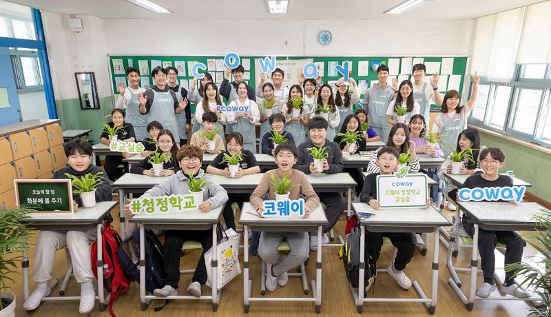 코웨이 직원들이 지난 13일 '코웨이 청정학교 교실숲 제5호'로 지정된 서울 강서초등학교에서 학생들과 함께 기념 촬영하고 있다. 코웨이 제공.