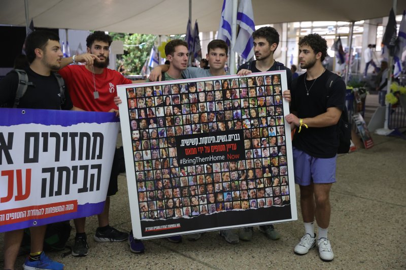 22일(현지시간) 이스라엘 텔아비브에서 시민들이 하마스에게 납치당한 인질들의 사진을 모아 들고 있다.EPA 연합뉴스