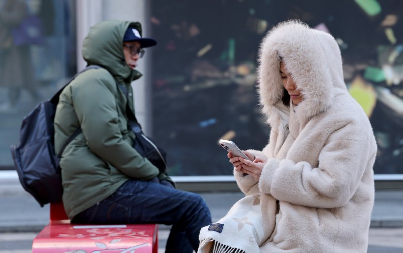 영하권 추위가 이어진 지난 12일 오전 서울 중구 명동거리를 찾은 관광객들이 두꺼운 외투를 입은 채 자리에 앉아 있다. 뉴스1