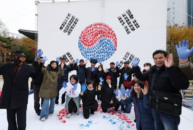 [서울=뉴시스] 고승민 기자 = 26일 서울 보신각 앞 광장에서 국학원 주최로 열린 '대한민국 100만 손도장 태극기몹' 캠페인에서 참가자들이 손도장으로 태극기에 색을 입힌 뒤 기념촬영하고 있다. 2023.11.26. kkssmm99@newsis.com