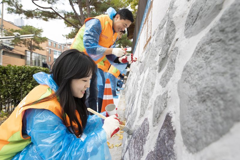 지난 4일부터 17일까지 서울 종로구 북촌한옥마을 미관 개선 활동에 참여한 현대건설 임직원들이 재동초등학교 담벼락에 전통 가옥 문양의 벽화를 그리고 있다. 현대건설 제공