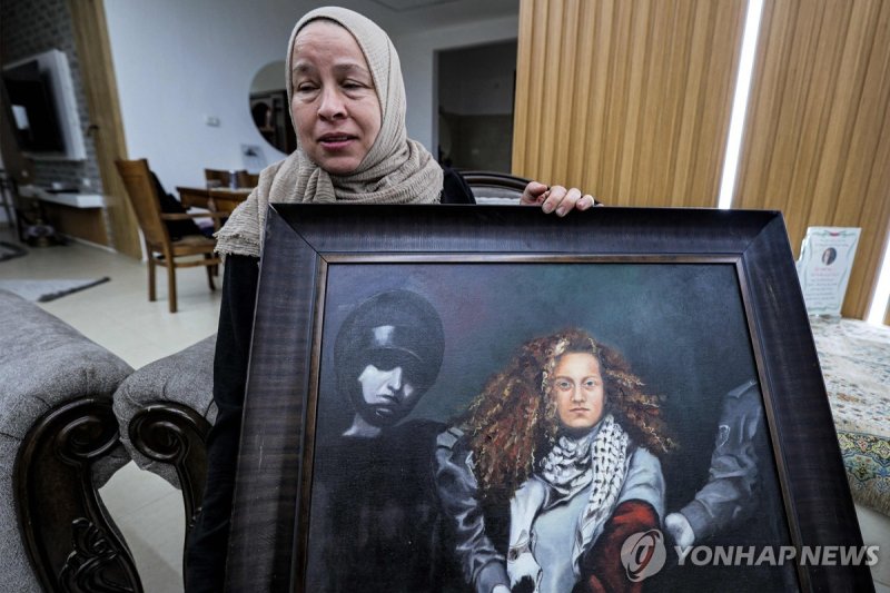 '팔레스타인 잔다르크' 아헤드 타미미 그림 들고 있는 어머니 Nariman Tamimi, mother of detained Palestinian activist Ahed Tamimi, holds a framed painting depicting her daughter as she sits in their family home in the village of Nabi Saleh in the occupied West Bank on November 6, 2023. The Israeli army said on November 6 it ha