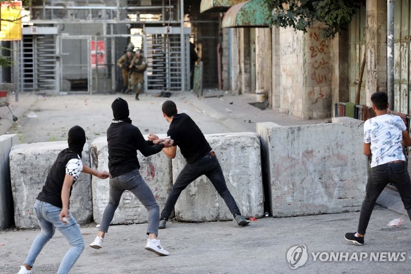 이스라엘군에 돌 던지는 팔레스타인 시위대 epa09513640 Palestinians throw stones at Israeli soldiers during clashes following a protest in the city center of the West Bank city of Hebron, 08 October 2021. Clashes erupted after a protest in solidarity with Palestinian prisoners jailed in Israel. Two Palestinians were ar