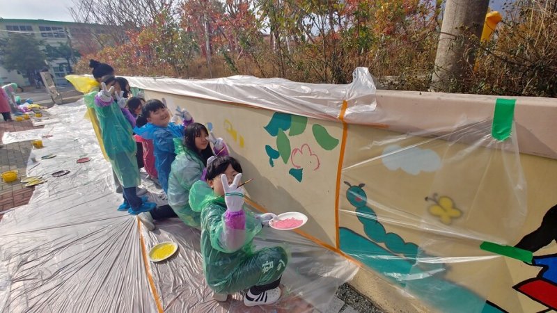 강진동초등학교(교장 고영운)- 27일 학생들이 아침 독서 시간에 읽은 책 속 한 장면을 학교 담장에 표현하는 벽화 그리기를 하고 있다.(전남교육청 제공)/뉴스1