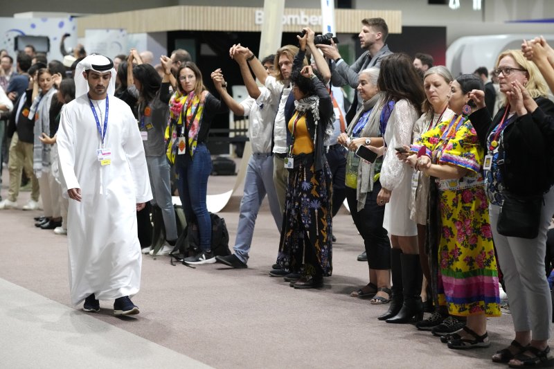 아랍에미리트연합(UAE) 두바이에서 열리고 있는 유엔 COP28 기후변화 회의에서 "모든 화석연료를 단계적으로 퇴출한다"는 문구가 합의문 초안에서 빠지면서 환경단체들이 강하게 반발하고 있다. UAE 협상팀원이 11일(현지시간) 두바이 협상장에 들어서는 가운데 시위대가 온실가스 감축을 요구하며 시위하고 있다. AP뉴시스