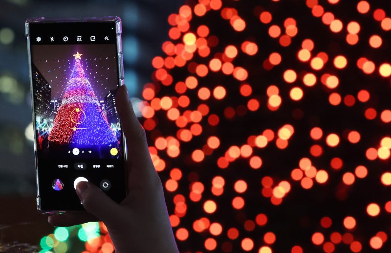 15일 오후 서울 세종대로 광화문광장에서 열린 ‘2023 서울빛초롱축제’에서 한 시민이 미디어트리를 스마트폰으로 촬영하고 있다. 이번 행사는 이날 개막해 내년 1월 21일까지 38일간 진행된다. 2023.12.15/뉴스1 ⓒ News1 김진환 기자