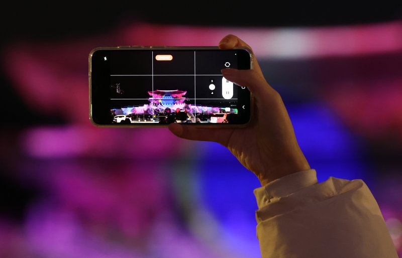 15일 오후 서울 세종대로 광화문광장에서 열린 ‘2023 서울빛초롱축제’에서 한 시민이 광화문 외벽에 투영되는 미디어파사드를 스마트폰으로 촬영하고 있다. 이번 행사는 이날 개막해 내년 1월 21일까지 38일간 진행된다. 2023.12.15/뉴스1 ⓒ News1 김진환 기자