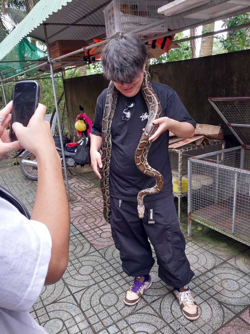 메콩 삼각주 투어 과정에서 큰 뱀을 목에 걸고 있는 관광객의 모습.