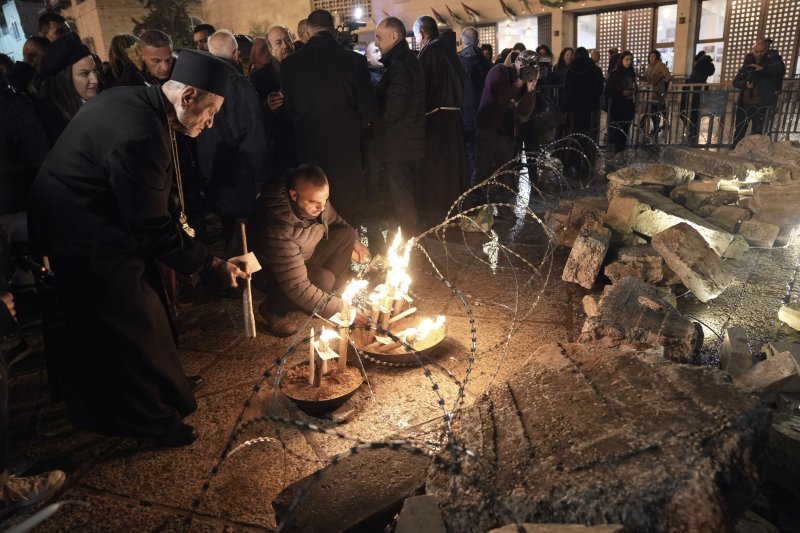 23일(현지시각) 요르단강 서안지구 베들레헴에 있는 예수탄생 교회 인근 구유 광장에서 한 사제와 남성이 가자지구 희생자들을 기리기 위한 그리스도 성탄화 앞에 촛불을 밝히고 있다. 이스라엘-하마스 전쟁으로 예수 탄생지 베들레헴은 조용히 크리스마스를 맞이하고 있다. 사진=AP·뉴시스