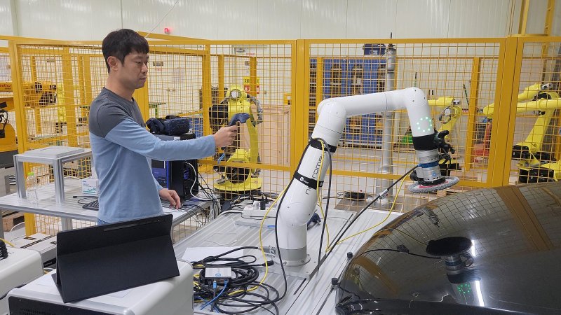 한국전자통신연구원(ETRI) 연구진이 로봇이 샌딩 작업을 하도록 작업 위치를 지정해 주고 있다. ETRI 제공
