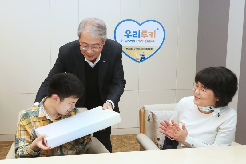 임종룡 우리금융그룹 회장(사진 가운데)이 지난 2일 서울 중구 우리금융 본사에서 '우리 루키(Look & Hear) 프로젝트'를 통해 시·청각 수술비를 지원받은 가족에게 선물을 전달하고 있다. 사진=우리금융제공