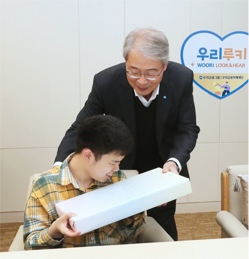임종룡 우리금융그룹 회장(오른쪽)이 지난 2일 서울 중구 우리금융 본사에서 '우리 루키(Look&Hear) 프로젝트'를 통해 시·청각 수술비를 지원받은 아동에게 선물을 전달하고 있다. 우리금융 제공