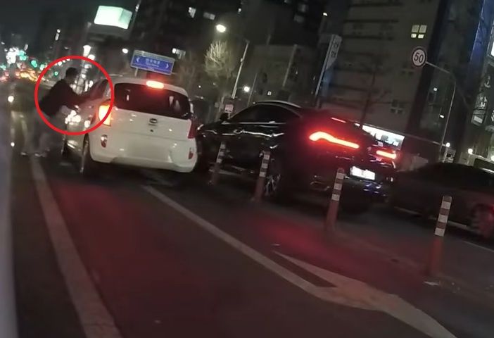음주운전을 하던 30대 남성이 신호 대기 중 잠이 들어 차가 내리막길을 따라 이동하자 이를 목격한 한 시민이 차를 급히 막아서고 있다./사진=유튜브 채널 '한문철TV'