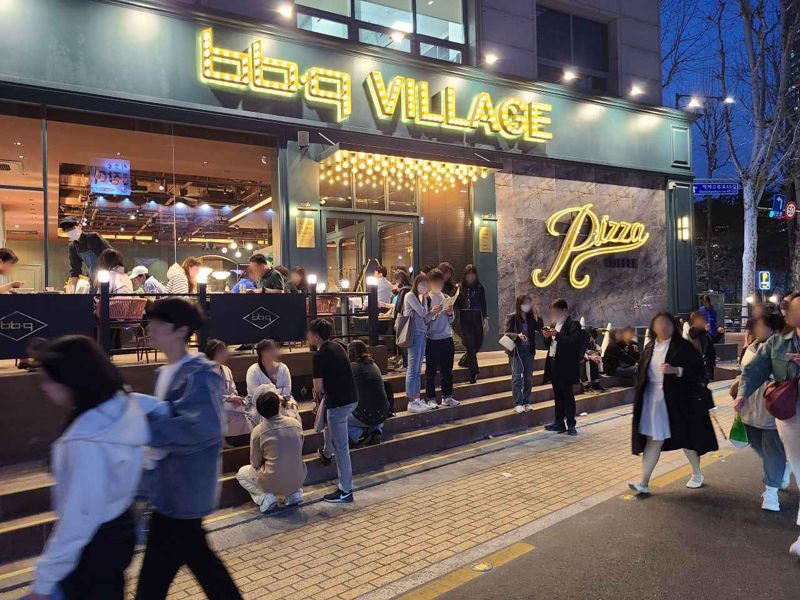 BBQ 빌리지 송리단길점 점포 앞에 고객들이 입장을 기다리고 있다.