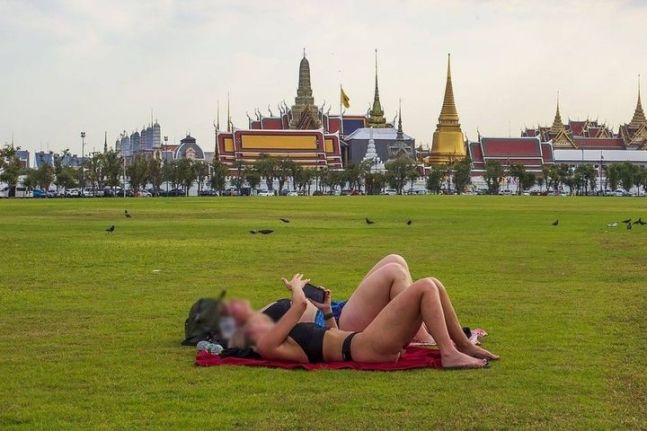 지난 12일 태국 수도 방콕 왕궁 앞 광장인 사남루앙에서 외국인 여성 2명이 비키니를 입고 누운 채 일광욕을 하다 경찰에 제지됐다. 사진=페이스북 캡처