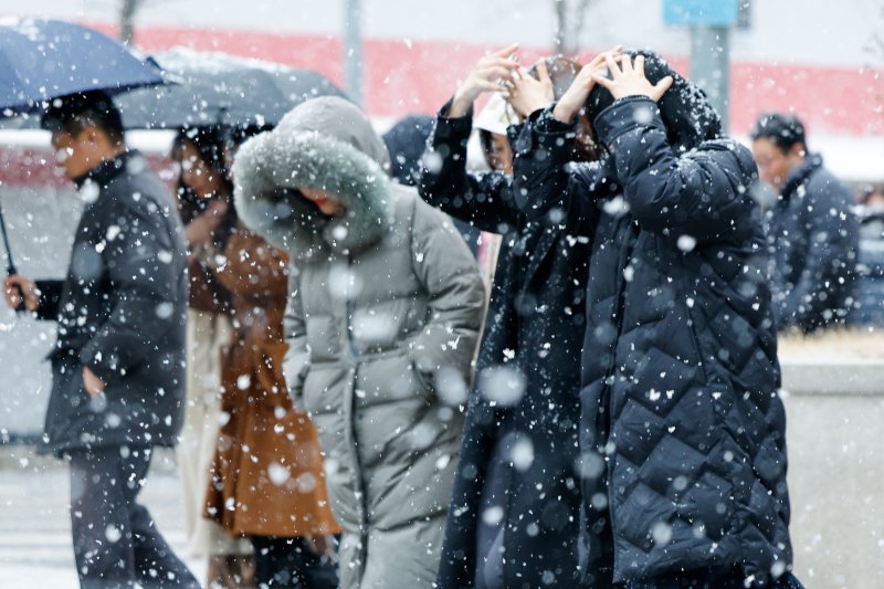 서울 지역에 눈이 내리는 17일 여의도에서 직장인들이 점심식사를 하기 위해 이동하고 있다. 뉴스1