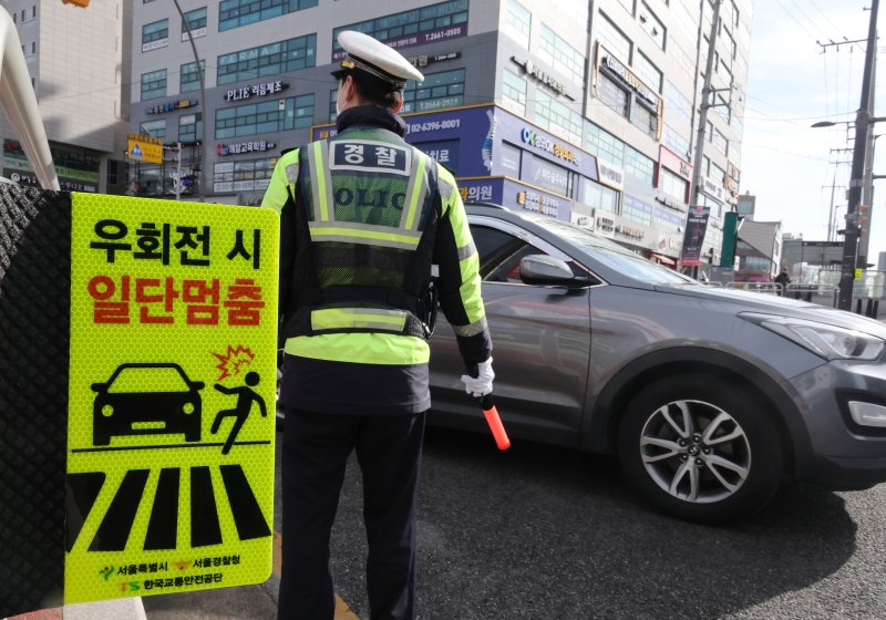 지난 19일 서울 강서구 한 교차로에서 경찰이 우회전 일시 정지 계도 및 단속 활동을 벌이고 있다. 연합뉴스