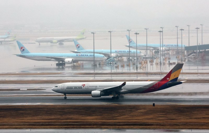 지난 14일 오후 인천국제공항 계류장에 세워진 대한항공 항공기 앞으로 아시아나 항공기가 이륙하고 있다. 뉴스 1