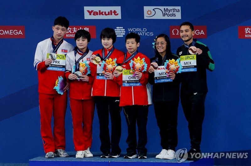 북한 다이빙, 세계선수권 다이빙 혼성 10ｍ 2위 Diving - World Aquatics Championships - Hamad Aquatic Centre, Doha, Qatar - February 3, 2024 Gold medallists China's Jianjie Huang and Jiaqi Zhang celebrate on the podium after winning the mixed 10m synchronised final alongside silver medallists North Korea's Jin Mi Jo an