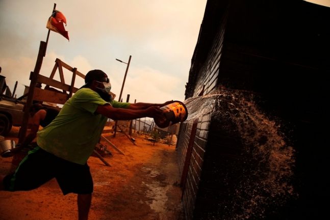 칠레 발파라이소주에서 3일(현지시간) 한 남성이 불을 끄기 위해 물을 뿌리고 있다. AFP연합뉴스