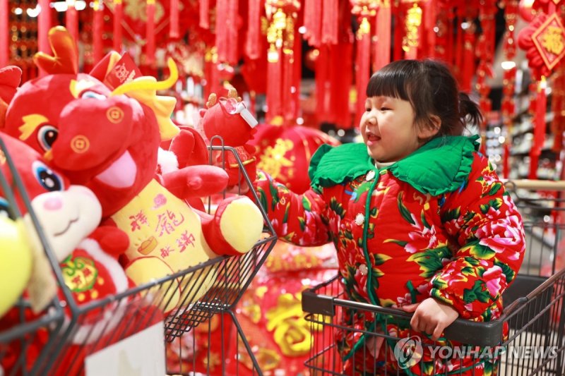 중국의 한 어린이가 13일 춘제 연휴를 맞아 쇼핑 센터에서 선물을 고르며 즐거워하고 있다. 연합뉴스