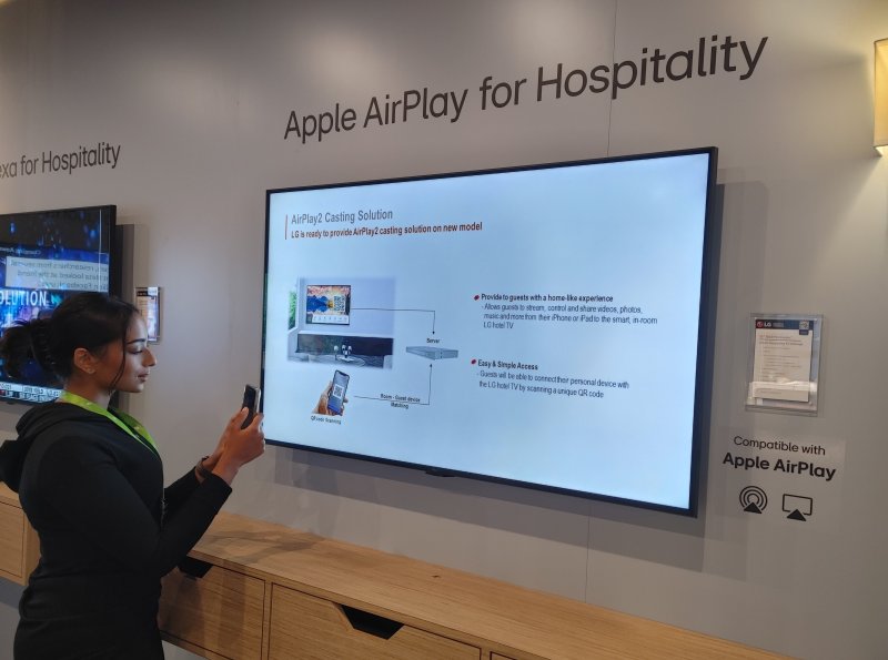LG전자 모델이 지난해 6월 미국 토론토에서 열린 호스피털리티 산업 박람회 HiTEC 2023에서 애플의 무선 콘텐츠 공유 기술인 에어플레이(Airplay) 기능이 적용된 세계 최초의 호텔 TV를 체험하고 있다. LG전자 제공