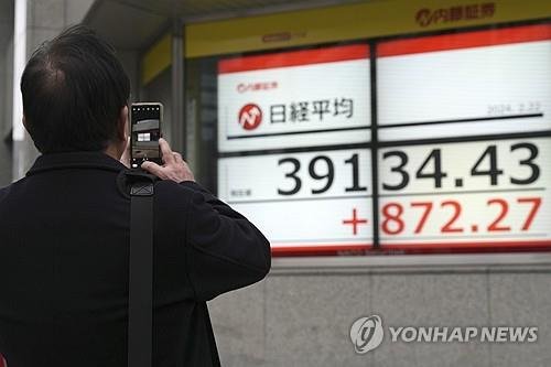 한 일본 시민이 전광판의 닛케이 평균주가를 사진으로 촬영하고 있다. 연합뉴스 제공