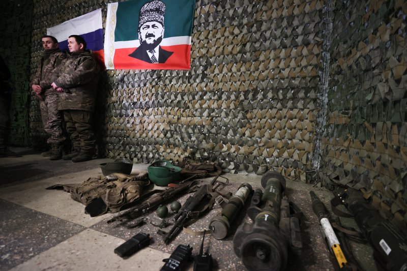 21일(현지시간) 위치가 알려지지 않은 우크라이나 전장에서 체첸 출신의 러시아 부대에 생포된 우크라 병사들이 항복 당시 소지했던 무기와 함께 사진을 찍고 있다.타스연합뉴스