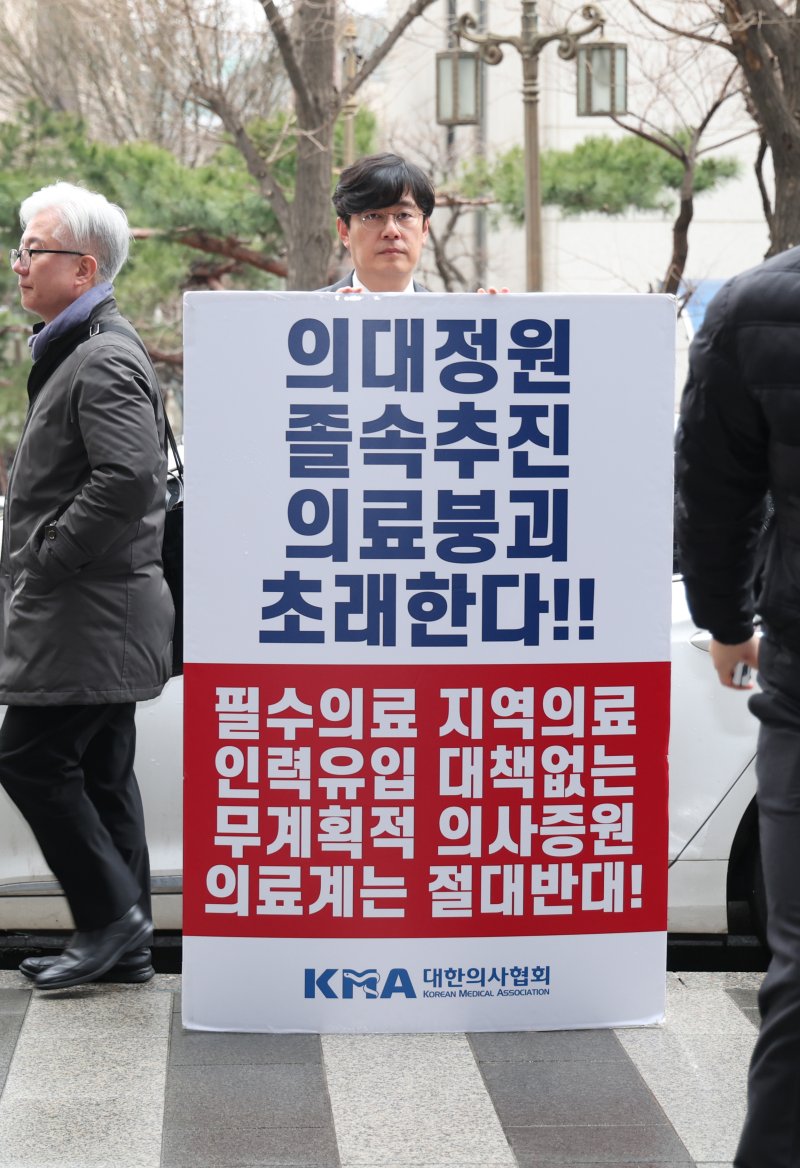 대한의사협회 한 관계자가 12일 서울경찰청 광역수사단 앞에서 피켓을 들고 있다. 이날 대한의사협회 김택우 비상대책위원장과 박명하 조직위원장은 전공의 파업 관련 조사를 받기 위해 수사단에 출석했다. 뉴시스