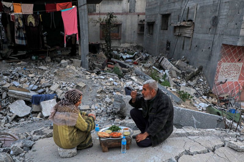 13일(현지시간) 팔레스타인 가자지구 중부의 디에르 엘 발라에서 현지 주민들이 무너진 집의 잔해에 앉아 식사를 하고 있다.신화연합뉴스