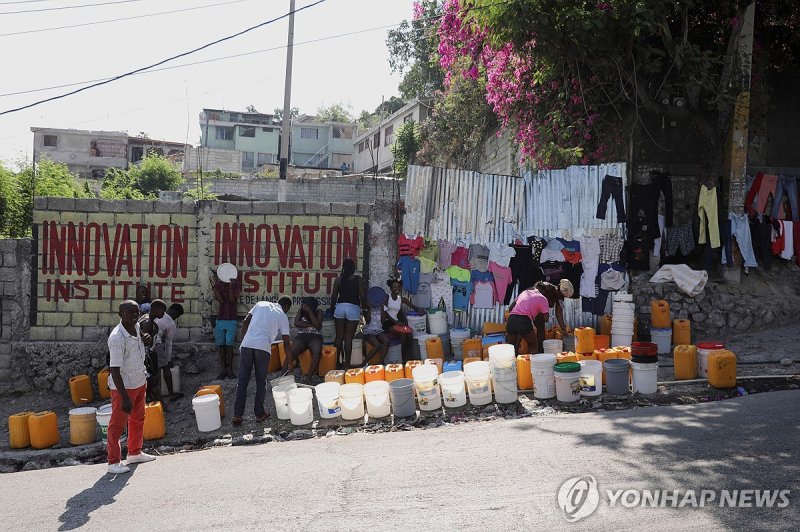 지난 12일(현지시간) 물을 받기 위해 기다리는 아이티 주민들 People line up along a street to collect water in buckets and containers after Haiti's Prime Minister Ariel Henry pledged to step down following months of escalating gang violence, in Port-au-Prince, Haiti March 12, 2024. REUTERS/Ralph Tedy Erol