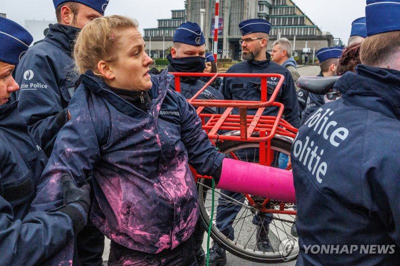 원자력정상회의 반대 시위 중 연행되는 참가자 epa11233145 Police personnel detain Greenpeace activists as they demonstrate on the sidelines of the Nuclear Energy Summit in front of the Atomium Monument in Brussels, Belgium, 21 March 2024. Heads of State and Government convene in Brussels for the first-ever Nuclear Energ