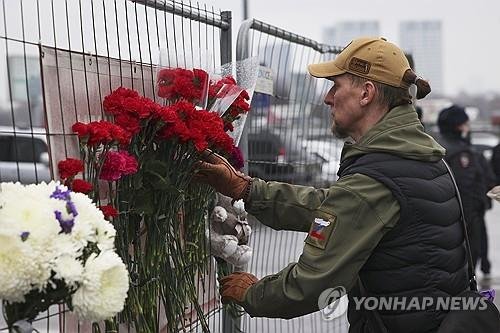 23일(현지시간) 하루전 테러가 발생한 러시아 모스크바 서쪽 크로커스 시티홀에서 발생한 테러와 관련해 한 남성이 공연장 울타리에 애도의 의미를 꽃을 놓고 있다. AP연합뉴스
